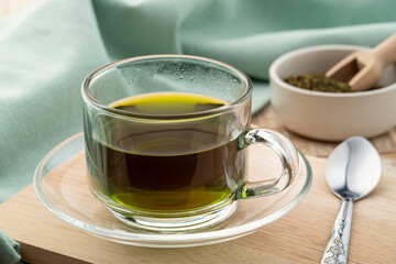 Hot green tea in glass cup on wooden table