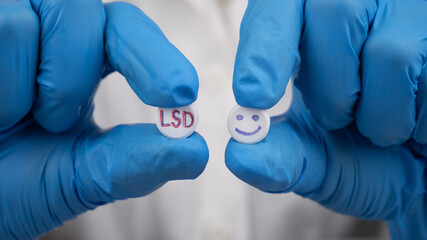 blue and red LSD pills in doctor hands, psychedelic drug for the treatment of severe stages of...