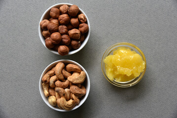 Delicious cashew nuts walnuts and hazelnuts with honey on a gray background. Delicious nuts in ceramic saucers and honey.