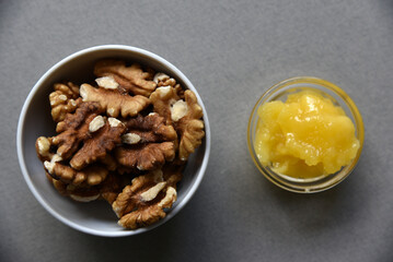 Delicious cashew nuts walnuts and hazelnuts with honey on a gray background. Delicious nuts in ceramic saucers and honey.