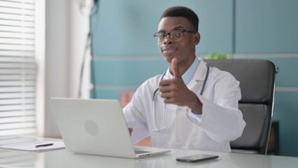 Fototapeta na wymiar Young African Doctor Showing Thumbs Up Sign While using Laptop in Office
