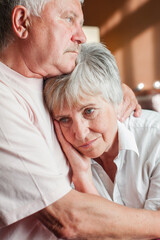 Worried senior woman embracing upset old man