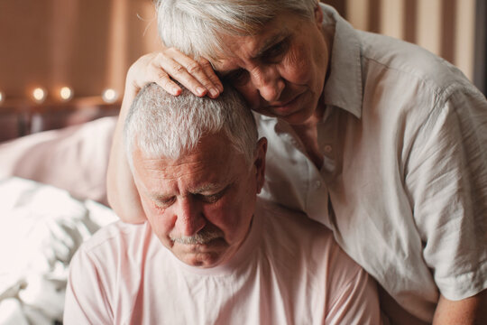 Worried senior woman embracing upset old man