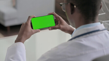 Young African Doctor Looking at Smartphone with Chroma Screen