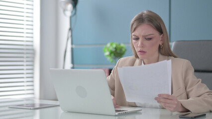 Businesswoman Upset while Reading Documents at Work