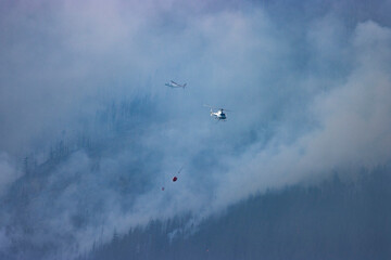 helicopters dropping water on forest fire in Alberta Canada