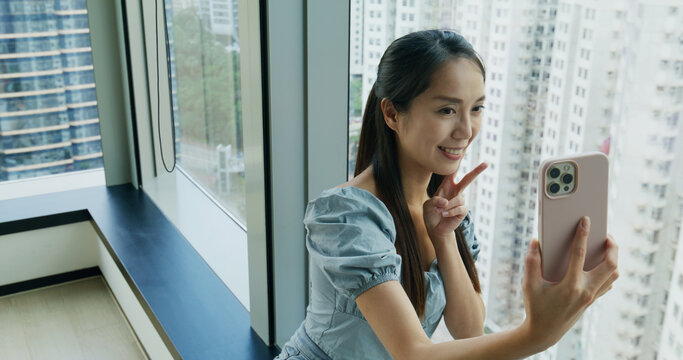 Woman take selfie on cellphone at room beside the big window