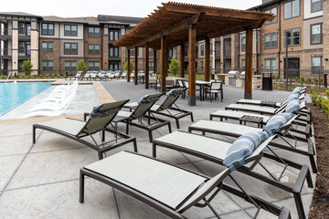 View on the chaise lounge chairs, swimming pool and rooftop dining area in modern residential...