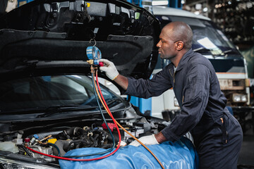 In the garage, mechanics examine and inspect the refrigerant before filling the car's air...
