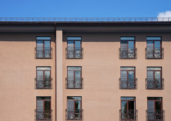 Fototapeta premium Windows in a brown hotel building or a hotel with a beautiful wrought iron fence