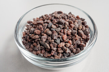 Black salt in glass bowl isolated in white background