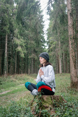 Naklejka na ściany i meble Yoga woman sitting and meditating in a forest.