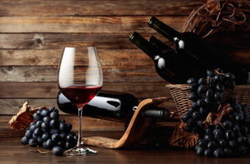 Red wine and blue grapes on an old wooden table. - obrazy, fototapety, plakaty