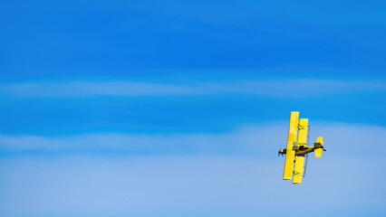 Yellow Crop duster in a vase blue sky