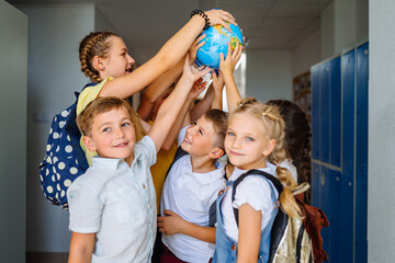 Different age team of children playing with globe in hallway at school. . Education, ecology, creativity and logical thinking concept.