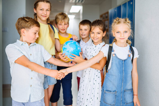 Teamwork concept. Group of five different age kids play globe ball in teamwork in school corridor at primary school. . Education, ecology, creativity and logical thinking concept.