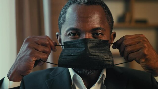 Male portrait serious adult businessman putting on medical mask protect health during pandemic responsible man in protective respirator looking at camera posing close-up complies quarantine measures