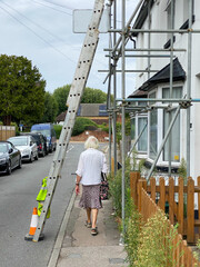 A caucasian female walking under a ladder in a residential area.