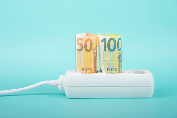 Euro money banknotes plugged in power strip extension cord on light blue background. Increasing electricity cost, rise electric price and expensive energy concept
