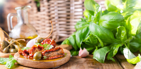 Capers and Dried tomatoes with herbs in olive oil.Large capers. Traditional appetizers in Italy with garlic, Provence herbs and basil. Ingredients for bruschetta and aperitif. High quality photo