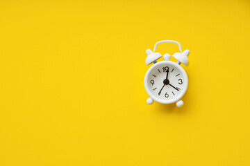 White alarm clock isolated on a yellow with copy space. Deadline concept