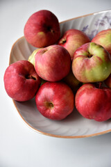 Red and yellow apples on a plate on a white background. Juicy fresh apples freshly washed in the kitchen.