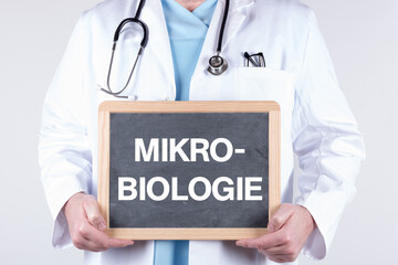 Arzt mit einer Tafel auf der MIKROBIOLOGIE steht