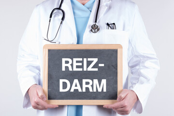 Arzt mit einer Tafel REIZDARM in den Händen