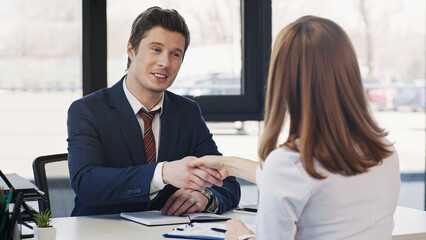 pleased businessman shaking hands with woman after job interview.