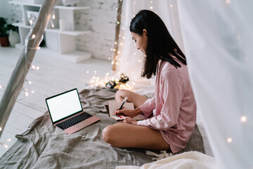 Asian woman writing in notebook in wigwam tent © BullRun
