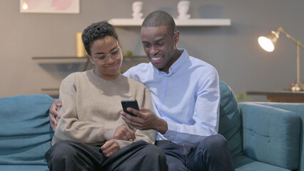 Fototapeta premium Couple using Smartphone While Sitting on Sofa