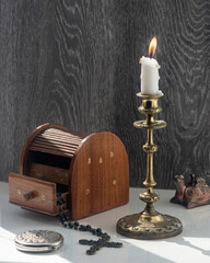 Candelabra with candle, inlaid jewelry box, women's mirror.A burning candle in a candelabra is the central composition of the still life.