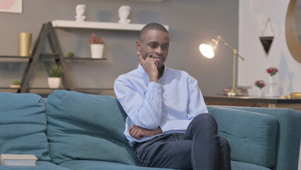 Pensive African Man Thinking While Sitting on Sofa