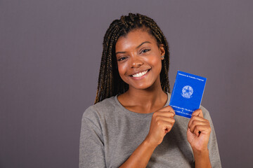 Young afro brazilian woman holding work card and social security. Official document, Human...
