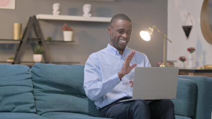 African Man Talking on Video Call on Laptop on Sofa