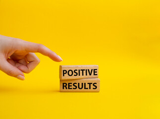Positive results symbol. Concept words 'Positive results' on wooden blocks. Beautiful yellow background. Businessman hand. Business and Positive results concept. Copy space.