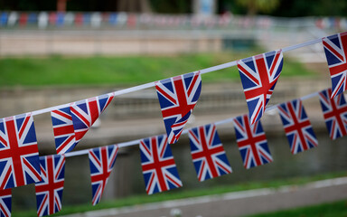 Fototapeta na wymiar Union Jack bunting flags flying in the wind with a green background 