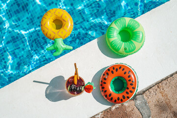 Drink at poolside. Swimming pool with inflatable rings. Vacation, beach, summer travel concept