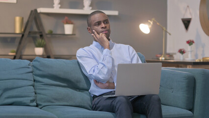 African Man with Laptop Thinking on Sofa