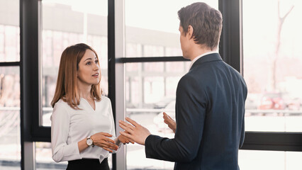 businessman and smiling woman gesturing during conversation on job interview.