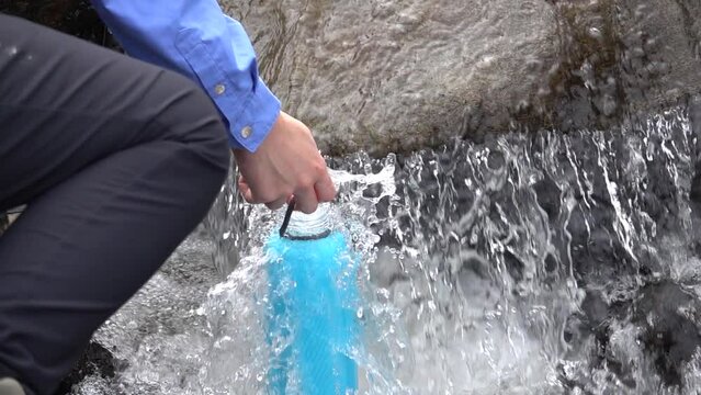 hiker filling water bottle from stream, Sweden

Beautiful slow motion shot from Sweden river, 2022
