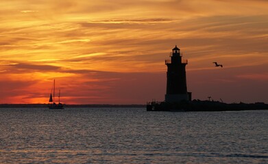 Silhouette of lighthouse and a yacht during sunset near Cape Henlopen State Park, Lewes, DE © Khairil