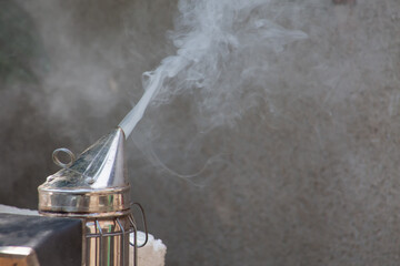 The chimney is smoking. Equipment for beekeeping close-up. Abstract smoke dispersed in the air