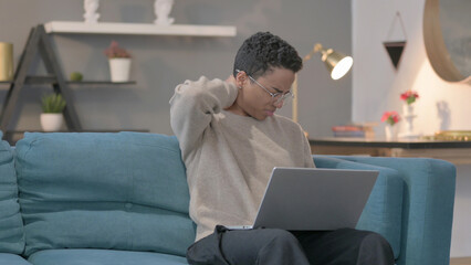 African Woman with Laptop having Neck Pain on Sofa