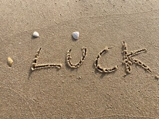 Fototapeta na wymiar on the beach is carved with letters in the smooth sand the writing Luck