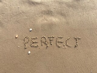 on the beach is carved with letters in the smooth sand the writing Perfect