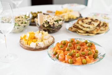 Fototapeta na wymiar Fantastic grazing table. Cheese and salad dish, wine glass, olives, salmon on table.