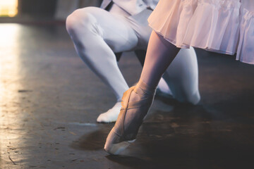 Ballet dancers couple during performance repetition, classic ballet rehearsal practicing in ballroom, view of legs in pointe shoes, ballerina and ballet dancer on a concert hall theatre stage © tsuguliev