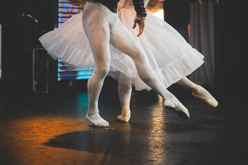 Ballet dancers couple during performance repetition, classic ballet rehearsal practicing in ballroom, view of legs in pointe shoes, ballerina and ballet dancer on a concert hall theatre stage © tsuguliev