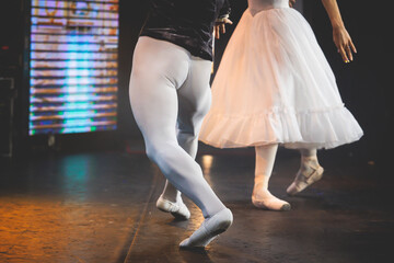 Ballet dancers couple during performance repetition, classic ballet rehearsal practicing in ballroom, view of legs in pointe shoes, ballerina and ballet dancer on a concert hall theatre stage © tsuguliev